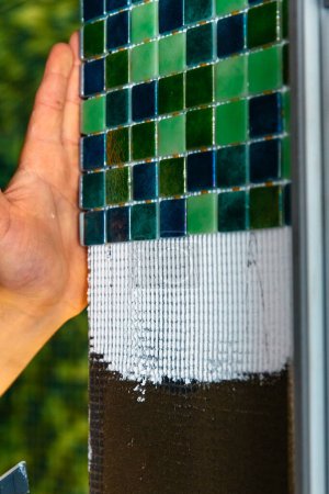Photo for "Applying modern mosaic tiles, sauna renovation" - Royalty Free Image