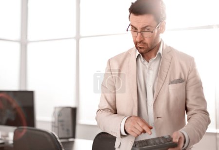 Téléchargez les photos : "homme d'affaires sérieux utilisant la calculatrice
." - en image libre de droit