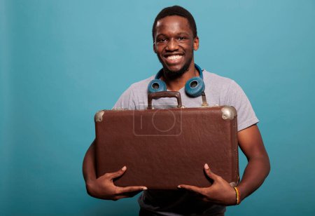 Téléchargez les photos : "Portrait de jeune homme tenant une valise rétro pour partir en voyage" - en image libre de droit