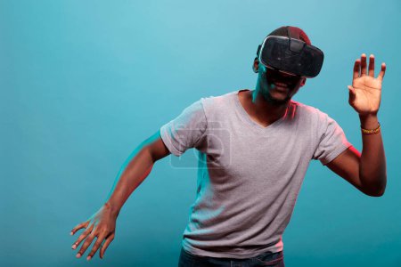 Photo for "Cheerful person raising hands and playing with futuristic vr goggles" - Royalty Free Image
