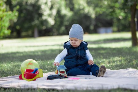 Téléchargez les photos : "joli petit garçon jouer avec un jouet voiture assis sur la pelouse
" - en image libre de droit