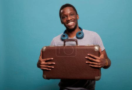 Téléchargez les photos : "Homme heureux portant des bagages mallette pour partir en vacances" - en image libre de droit
