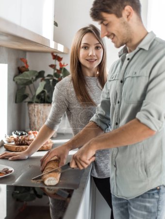 Téléchargez les photos : "heureux jeune couple avec de la nourriture dans leur nouvelle cuisine - en image libre de droit