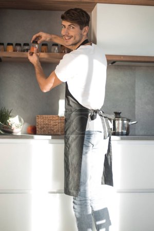 Foto de "Vista trasera. un hombre elige especias para cocinar la cena
" - Imagen libre de derechos