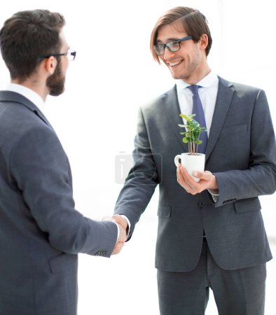 Foto de Hombre de negocios con un arbolito estrechando la mano con un socio
. - Imagen libre de derechos