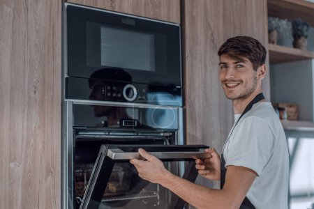 Téléchargez les photos : En pleine croissance. attrayant jeune homme debout dans la cuisine maison - en image libre de droit