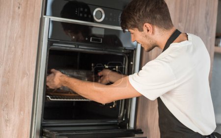 Foto de Hombre abriendo el horno en la cocina del hogar - Imagen libre de derechos