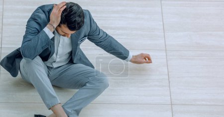 Photo for "frustrated young businessman sitting on the floor and looking down." - Royalty Free Image