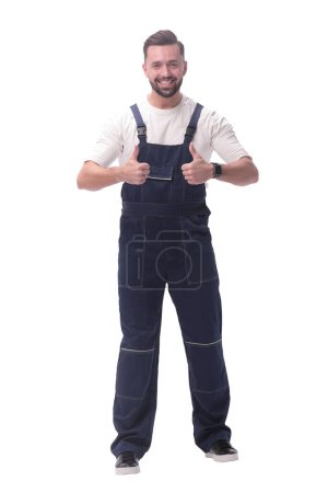 Photo for "in full growth. friendly man in overalls showing thumbs up" - Royalty Free Image