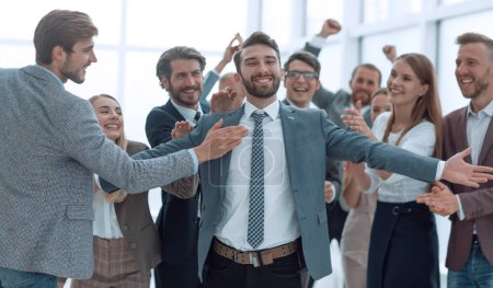 Téléchargez les photos : Jubilant jeune homme d'affaires acceptant les félicitations de son équipe d'affaires. - en image libre de droit