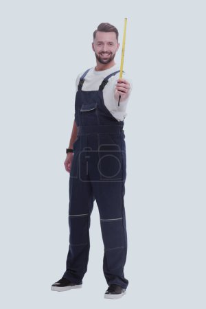 Téléchargez les photos : "homme en salopette avec un ruban à mesurer de construction. isolé sur blanc" - en image libre de droit