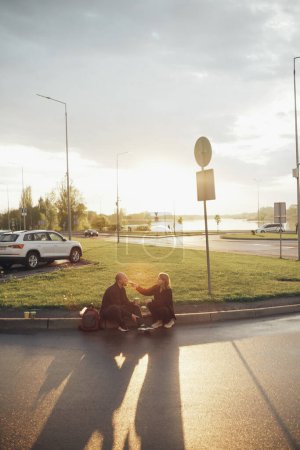 Téléchargez les photos : "amateurs mangent pizza assis sur la pelouse pendant le coucher du soleil" - en image libre de droit