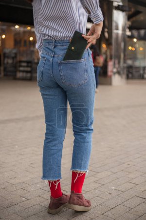 Foto de Mujer confiada posando en guardar guardando su billetera en el bolsillo trasero - Imagen libre de derechos