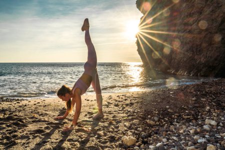 Téléchargez les photos : Gymnaste fille s'entraîne sur la plage au coucher du soleil de mer. Ça fait du fil. Série photo. - en image libre de droit