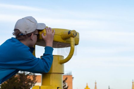 Téléchargez les photos : Garçon regardant à travers binoculaire à la ville - en image libre de droit