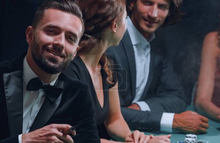 Téléchargez les photos : Homme avec cigare levant les yeux du jeu de poker au casino - en image libre de droit