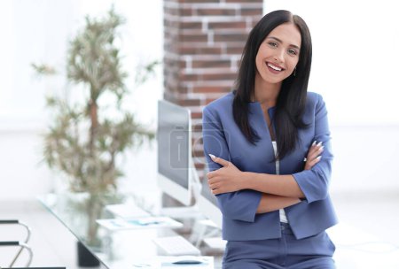 Photo for "Attractive young businesswoman standing near desk in the office" - Royalty Free Image