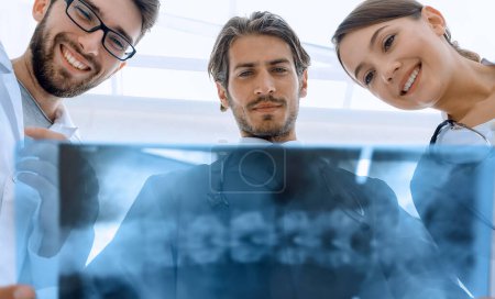 Photo for Three doctors studying the patient's X-ray film - Royalty Free Image