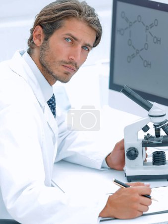 Téléchargez les photos : "Travailleur de laboratoire assis à table avec microscope
" - en image libre de droit