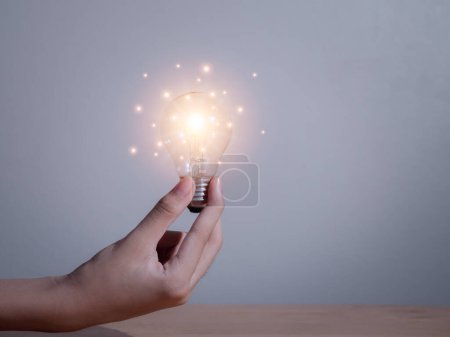 Photo for "Hand of businessman holding light bulb with fire spark shine glitter for new idea with innovation and inspiration, communication and technology in science concept." - Royalty Free Image