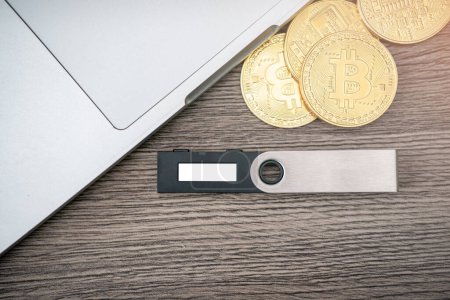 Téléchargez les photos : "Portefeuille matériel crypto-monnaie avec Bitcoin doré (BTC) et ordinateur. Stockage sûr pour crypto. " - en image libre de droit