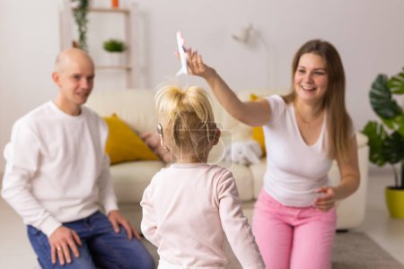 Foto de Cochlear implant on the child girl head and playing with mother and father. Hearing aid and deafness and innovative health technology concept - Imagen libre de derechos