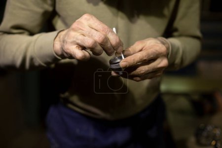 Photo for "Valve from spray gun in hands. Repair parts of paint remote. Cleaning valve." - Royalty Free Image