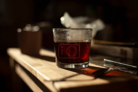 Téléchargez les photos : "Thé en verre. Détails de la cuisine. Boisson chaude le matin. Thé noir fort." - en image libre de droit