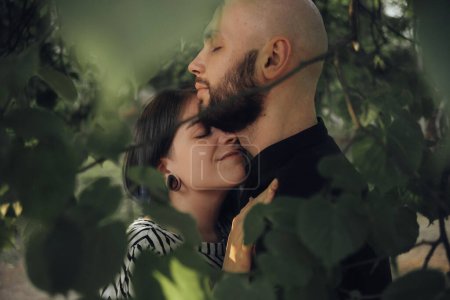 Téléchargez les photos : "le couple amoureux caché de tout le monde dans le feuillage de l'arbre. étreinte doucement" - en image libre de droit
