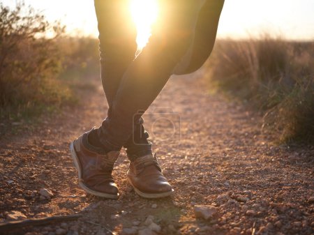 Foto de "piernas de la persona cruzadas con el sol que pasa a través de ellos al atardecer en la naturaleza" - Imagen libre de derechos
