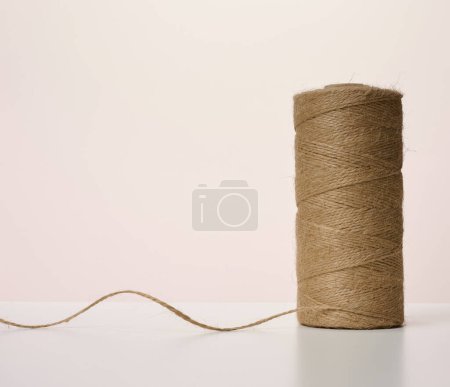 Foto de "Skein of brown eco-friendly jute rope on a beige background" - Imagen libre de derechos