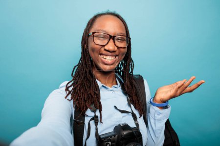 Téléchargez les photos : "Joyeux souriant chaleureusement afro-américain photographe professionnel enregistrant quotidiennement vlog vidéo." - en image libre de droit
