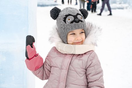Photo for Little girl in a knitted hat and scarf and ice sculptures - Royalty Free Image