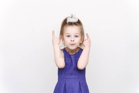 Téléchargez les photos : Petite fille émotionnelle dans une robe bleue. les pouces levés. - en image libre de droit