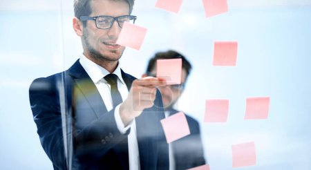 Photo for Serious employee reads a sticker-note on the office Board. - Royalty Free Image