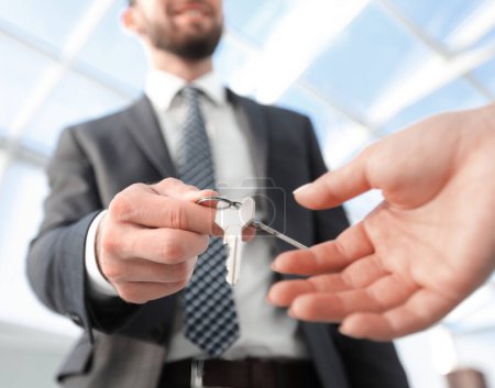 Téléchargez les photos : Image recadrée d'un agent immobilier donnant des clés de maison à un homme au bureau - en image libre de droit