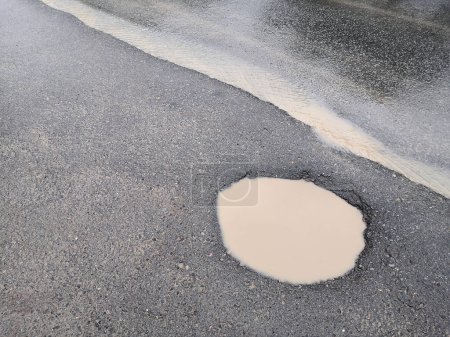 Photo for Hole and puddle on bad broken road. destroyed Road with Puddle. Bad road. Puddles and dirt on dirt road. - Royalty Free Image