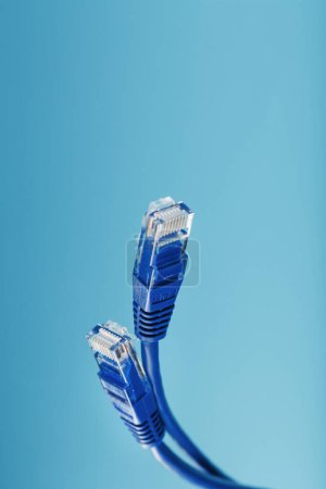 Foto de Two Ethernet Cable Connectors Patch cord cord close-up isolated on a blue background with free space - Imagen libre de derechos