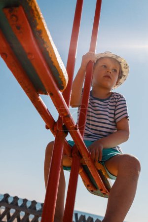 Téléchargez les photos : Petit garçon sur une balançoire d'équilibre, vue du bas. - en image libre de droit