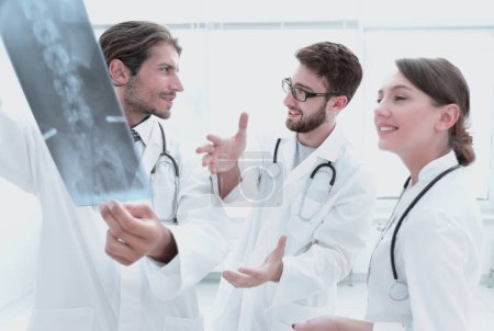 Téléchargez les photos : "Trois médecins confiants examinent une radiographie
" - en image libre de droit