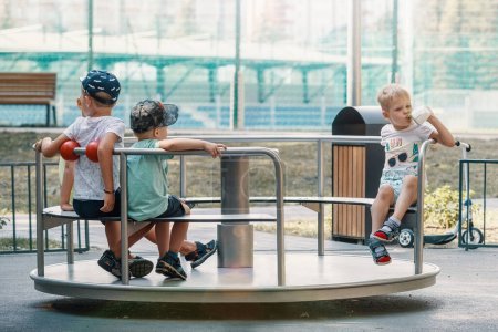 Foto de Los niños juegan en el parque infantil durante las vacaciones de verano. Carrusel para niños en verano en el parque. - Imagen libre de derechos