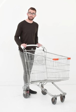 Photo for "Young man with empty shopping cart, isolated on white" - Royalty Free Image