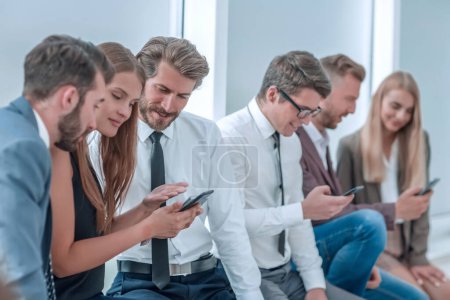 Foto de "jóvenes empleados de la empresa mirando las pantallas de sus teléfonos inteligentes" - Imagen libre de derechos