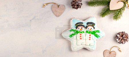 Foto de "Pan de jengibre de Navidad con muñecos de nieve sobre un fondo gris con ramas de abeto y conos. enfoque suave." - Imagen libre de derechos