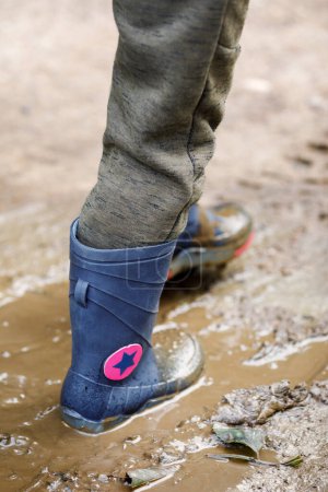 Photo for "Dirty little boy rubber boots in blue. Waterproof footwear for agricultural activity, gardener working, autumn concept" - Royalty Free Image