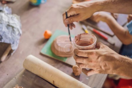 Téléchargez les photos : "Père et fils faisant pot en céramique dans l'atelier de poterie
" - en image libre de droit