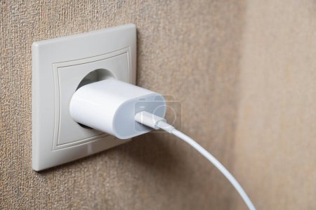 Photo for "charger in the socket on the wall, close-up" - Royalty Free Image
