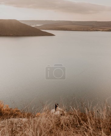 Foto de "pareja de boda en el amor de pie en la Piedra Grande en el acantilado y beso. vista panorámica" - Imagen libre de derechos