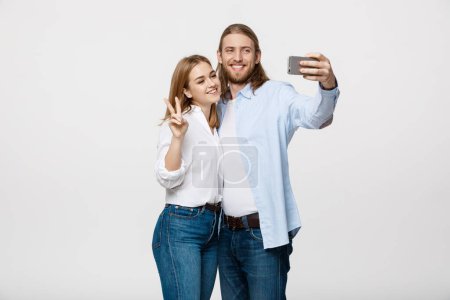 Téléchargez les photos : "Portrait d'un couple heureux faisant selfie photo avec smartphone sur fond de studio blanc isolé
." - en image libre de droit