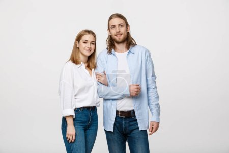 Photo for "Portrait of attractive young couple smiling for the camera while holding arm to arm. On grey background." - Royalty Free Image